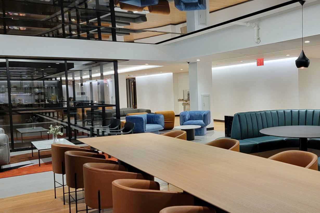 A WorkLife Office Suites by Industrious common area featuring a long, light brown conference table and eight brown leather chairs.