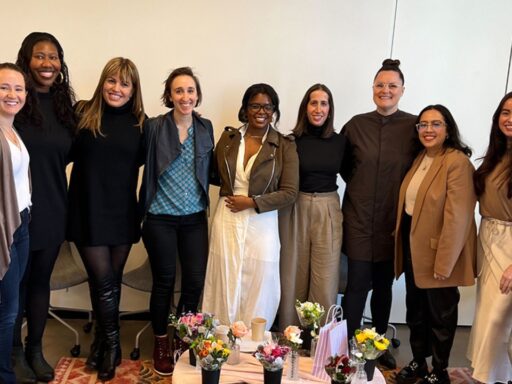 Several members of the Women@Industrious employee resource group are gathered for an event, huddled together and smiling for a photo.